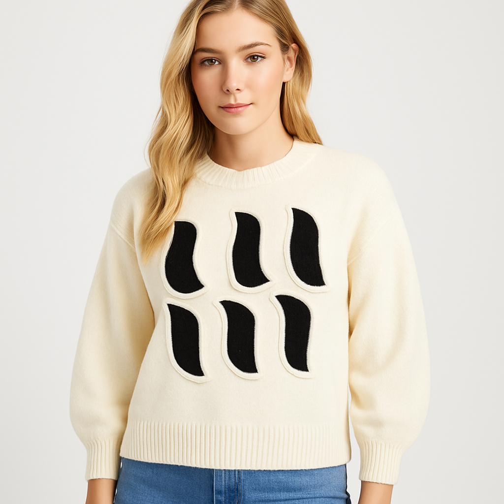 Cream knit sweater with bold black abstract appliqué design on the front and long sleeves.