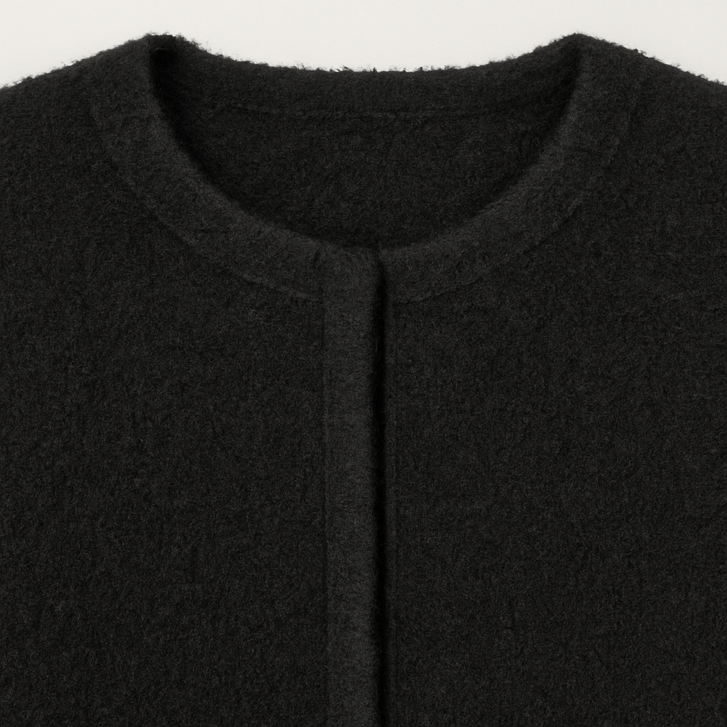 Black knit cardigan with long sleeves and fringe detailing on the cuffs.